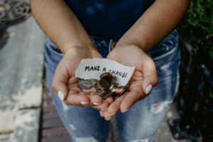 Person holding change in palms of hands with a small sign